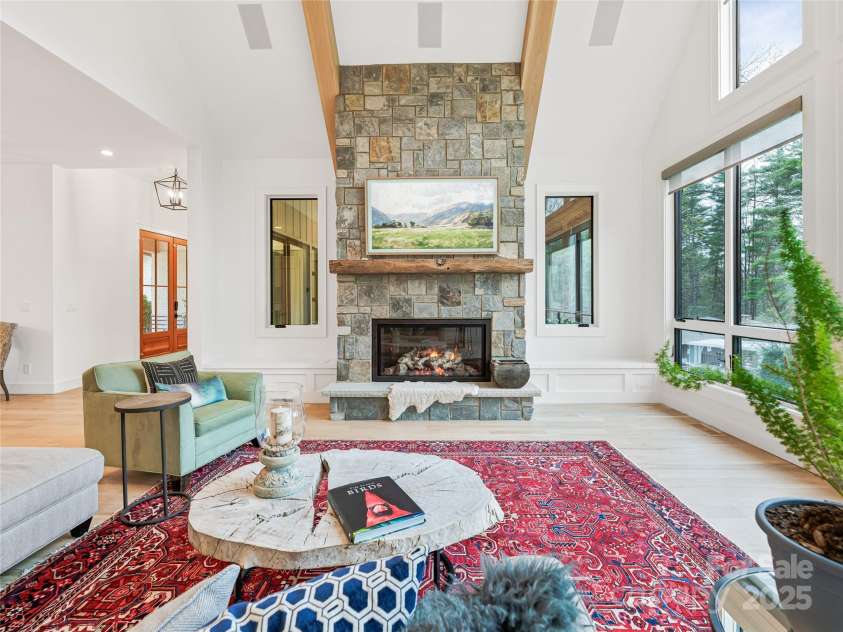 165 Robinhood Road, Asheville, NC 28804.  MLS# CAR4240751, YatesRealty ID 4309. Bright and airy living room featuring white oak floors, a striking stone gas fireplace, built-in speakers, and a TV seamlessly framed above the mantel.