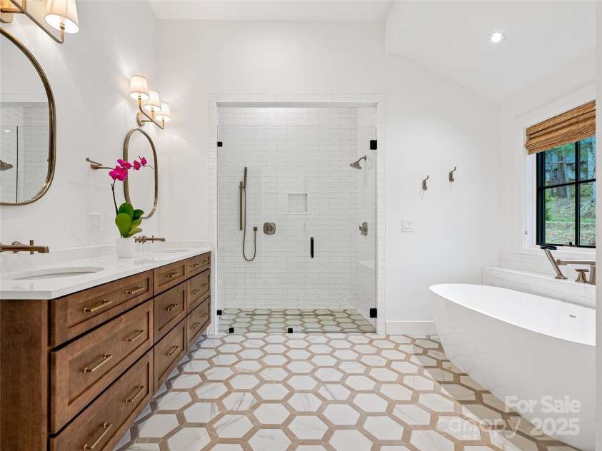 165 Robinhood Road, Asheville, NC 28804.  MLS# CAR4240751, YatesRealty ID 4309. Spa-inspired primary bath with sleek tile flooring, a walk-in shower, soaking tub, double vanity, and private water closet.
