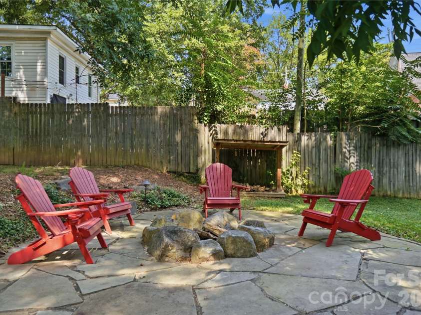 315 Pendleton Street, Rock Hill, SC 29730.  MLS# CAR4412482, YatesRealty ID 44209. A stone fire pit surrounded by mature trees creates a cozy gathering spot for evenings outdoors.