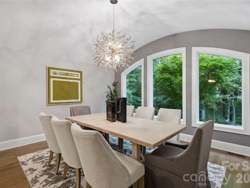 5023 Gorham Drive, Charlotte, NC 28226.  MLS# CAR4402221, YatesRealty ID 44262. Elegant formal dining room framed by dramatic arched windows overlooking the lush wooded setting, pairing architectural interest, abundant natural light and a statement chandelier for memorable entertaining.