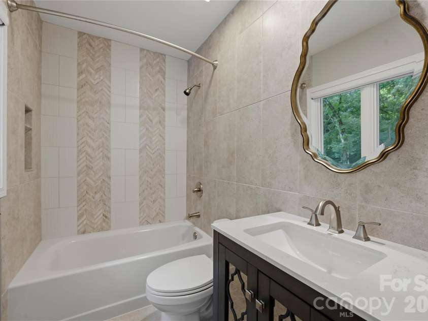 5023 Gorham Drive, Charlotte, NC 28226.  MLS# CAR4402221, YatesRealty ID 44262. Sophisticated secondary bath featuring a statement mirror, stone topped vanity and beautifully selected finishes that continue the home’s elevated design throughout.