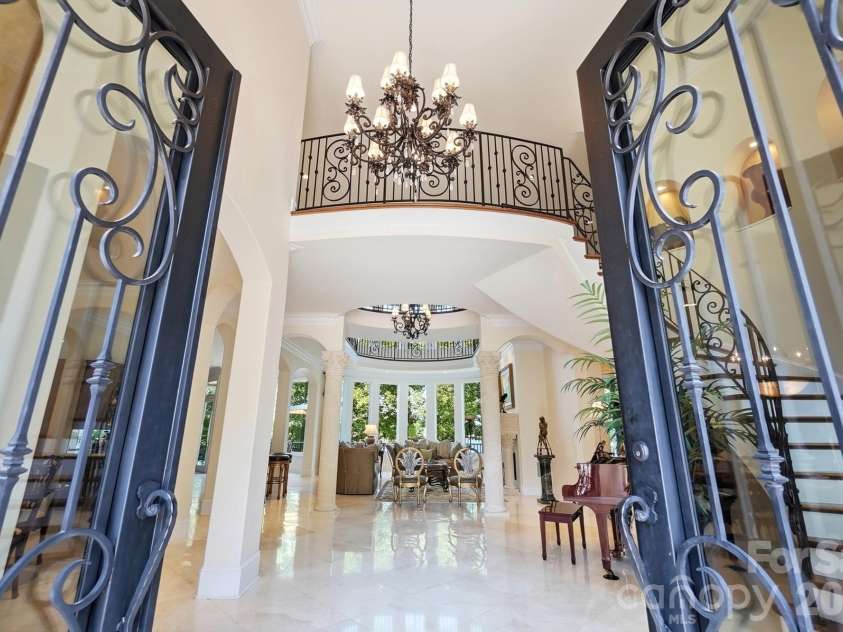 20124 Bascom Ridge Drive, Cornelius, NC 28031.  MLS# CAR4408389, YatesRealty ID 44623. A dramatic first impression begins at the grand two-story foyer, where custom wrought-iron and glass entry doors open to an elegant, light-filled interior. A statement chandelier, sweeping Brazilian cherry stairca