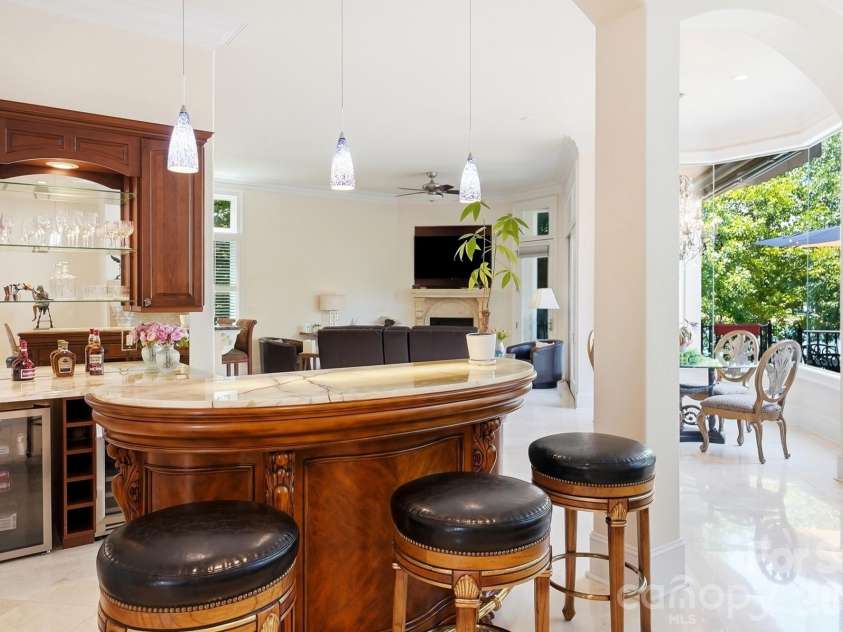 20124 Bascom Ridge Drive, Cornelius, NC 28031.  MLS# CAR4408389, YatesRealty ID 44623. A true showpiece for entertaining, the custom curved bar features a striking backlit onyx countertop that creates a warm, dramatic glow and highlights the stone’s natural veining. Rich wood cabinetry, glass displa