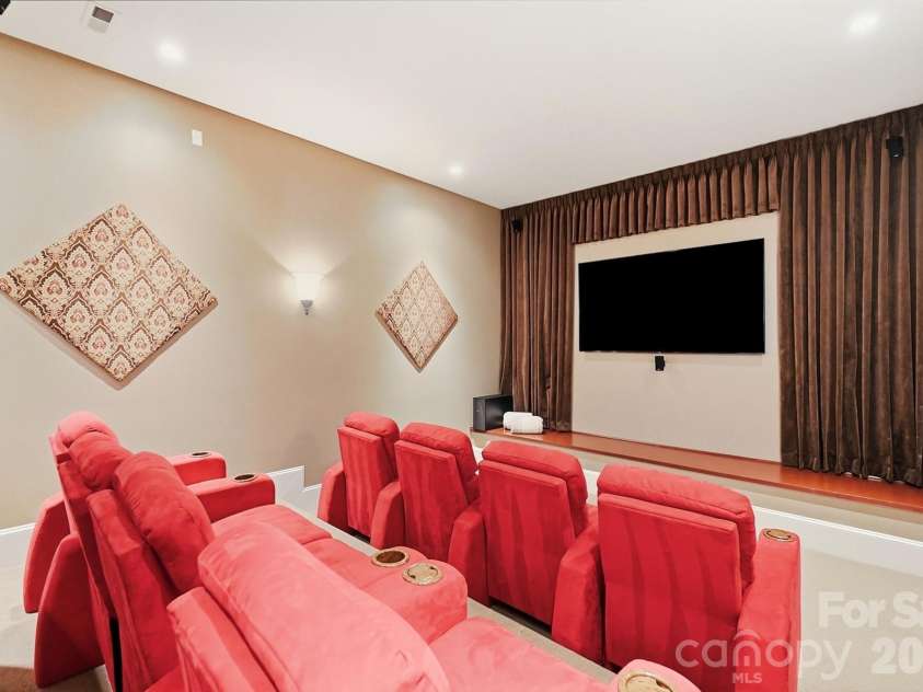 20124 Bascom Ridge Drive, Cornelius, NC 28031.  MLS# CAR4408389, YatesRealty ID 44623. Creatively connected to the lower-level entertaining area is a home theater designed for movie nights and game days with tiered seating, multiple theater-style recliners, a large screen, and integrated speakers fo
