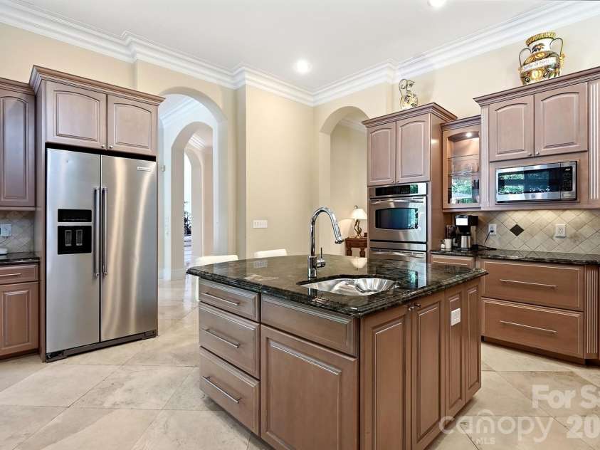 20124 Bascom Ridge Drive, Cornelius, NC 28031.  MLS# CAR4408389, YatesRealty ID 44623. From the opposite side, the expansive center island provides additional prep space, storage, a sink, and convenient seating. The kitchen remains visually connected to the adjoining casual living and outdoor areas,
