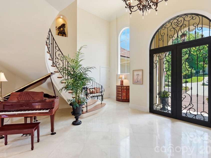20124 Bascom Ridge Drive, Cornelius, NC 28031.  MLS# CAR4408389, YatesRealty ID 44623. Step through the ornate iron-and-glass double doors into a soaring, light-filled foyer designed to make an immediate impression. Polished stone flooring, a sweeping curved staircase with decorative ironwork, a sta