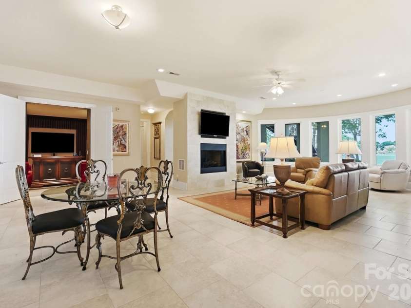 20124 Bascom Ridge Drive, Cornelius, NC 28031.  MLS# CAR4408389, YatesRealty ID 44623. The lower-level entertaining area offers a relaxed gathering space with a fireplace, generous seating area, and a sweeping wall of windows. Its proximity to the wine cellar and other recreation spaces makes it ide