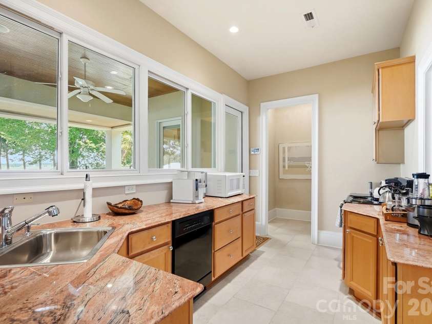20124 Bascom Ridge Drive, Cornelius, NC 28031.  MLS# CAR4408389, YatesRealty ID 44623. The lower level includes a convenient secondary kitchenette with granite countertops, ample cabinetry, a sink, dishwasher, and additional prep space. Large interior windows maintain the connection to the covered l