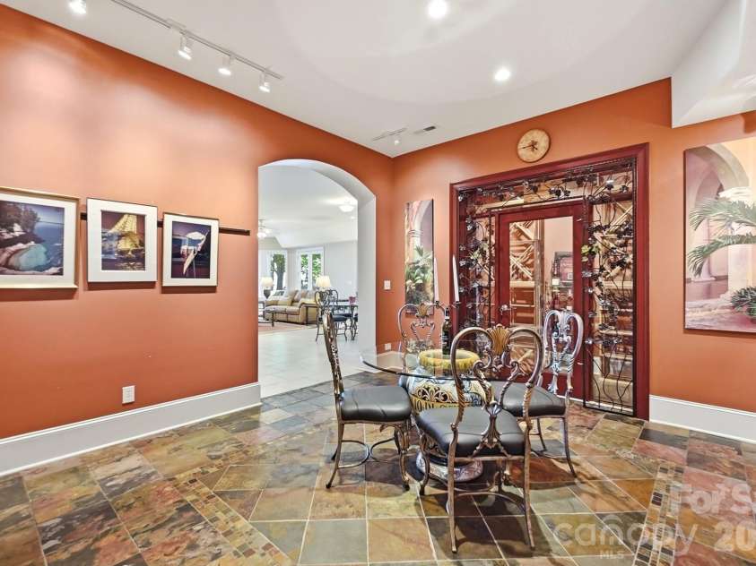 20124 Bascom Ridge Drive, Cornelius, NC 28031.  MLS# CAR4408389, YatesRealty ID 44623. The lower level opens to a distinctive gallery-style entertaining space with richly colored slate flooring, track lighting for artwork, and generous room for dining, games, or casual gatherings. The back staircase