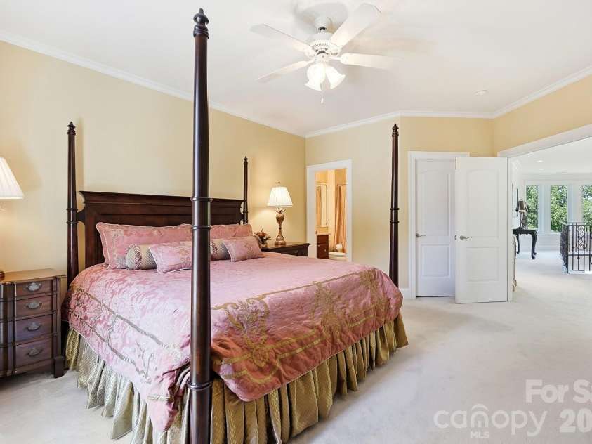 20124 Bascom Ridge Drive, Cornelius, NC 28031.  MLS# CAR4408389, YatesRealty ID 44623. This spacious secondary bedroom offers a comfortable private retreat with generous proportions, crown molding, a ceiling fan, and direct access to its own en suite bath. The open doorway also provides a glimpse ba