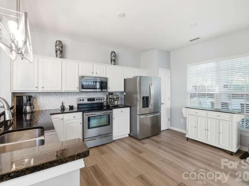 8530 Heron Glen Drive, Charlotte, NC 28269.  MLS# CAR4410893, YatesRealty ID 44779. Kitchen with granite counters, stainless appliances, updated tile backsplash, and laminate flooring