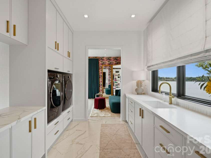 123 Cove Point, Mount Gilead, NC 27306.  MLS# CAR4408189, YatesRealty ID 44817. Laundry room connecting his and her closets featuring marble counters, custom cabinetry, a folding area, and a sink (upper level)