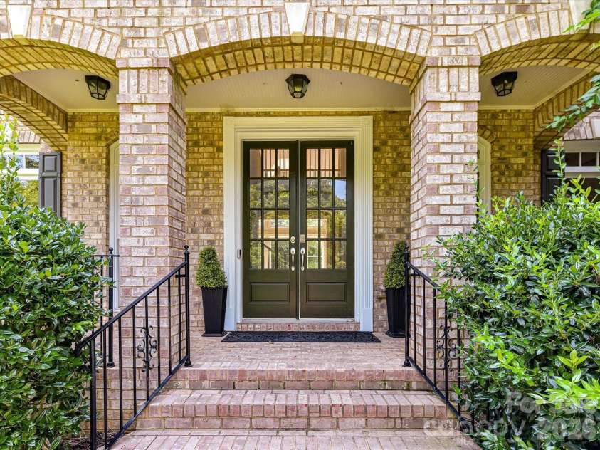 447 Three Greens Drive, Huntersville, NC 28078.  MLS# CAR4414048, YatesRealty ID 44824. A welcoming covered brick entry with elegant double doors and classic architectural details creates a warm and inviting first impression.