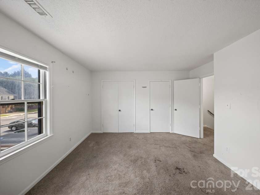 6835 Farmingdale Drive, Charlotte, NC 28212.  MLS# CAR4412722, YatesRealty ID 44983. Inviting primary bedroom with a spacious layout, large windows for natural light, plush carpeting, and ample closet storage.