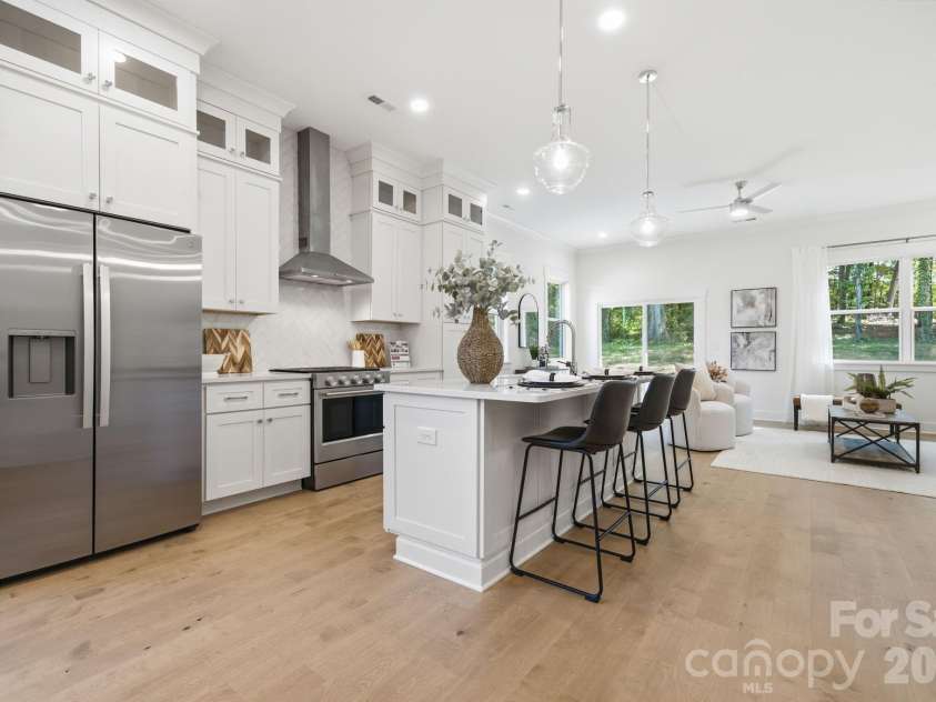 612 Camelot Drive, Salisbury, NC 28144.  MLS# CAR4411574, YatesRealty ID 45149. The bright, open kitchen features quartz countertops, beautiful flat iron bianco herringbone backsplash, ceiling-height stacked cabinets, a large island, gas range, walk-in pantry, & upgraded KitchenAid appliances