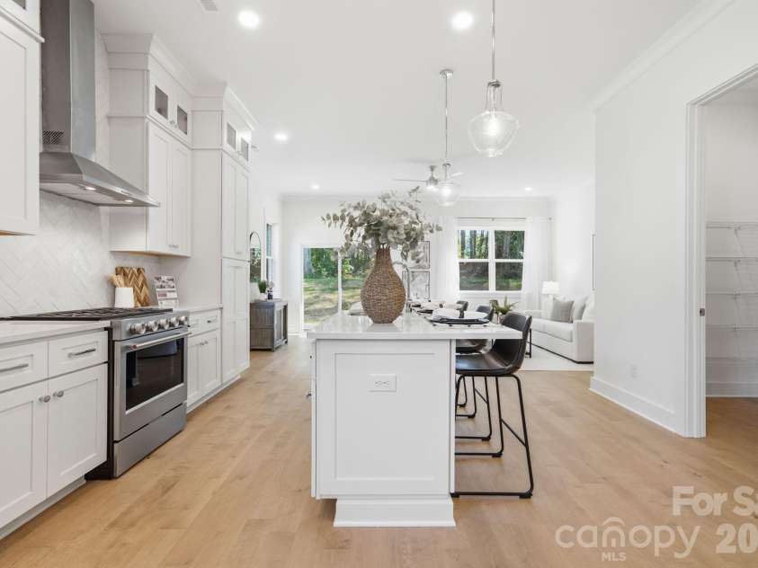 612 Camelot Drive, Salisbury, NC 28144.  MLS# CAR4411574, YatesRealty ID 45149. The bright, open kitchen features quartz countertops, beautiful flat iron bianco herringbone backsplash, ceiling-height stacked cabinets, a large island, gas range, walk-in pantry, & upgraded KitchenAid appliances