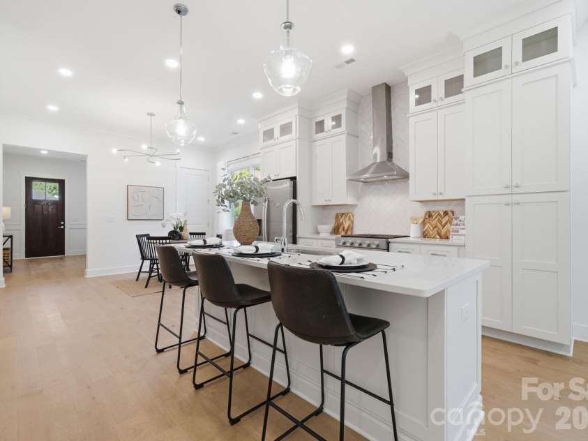 612 Camelot Drive, Salisbury, NC 28144.  MLS# CAR4411574, YatesRealty ID 45149. The bright, open kitchen features quartz countertops, beautiful flat iron bianco herringbone backsplash, ceiling-height stacked cabinets, a large island, gas range, walk-in pantry, & upgraded KitchenAid appliances