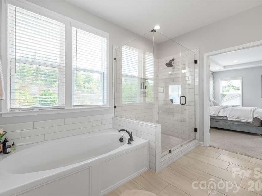 6440 Ancient Way, Fort Mill, SC 29707.  MLS# CAR4413430, YatesRealty ID 45254. A spa-like retreat featuring a luxurious soaking tub and a spacious walk-in shower with a modern frameless glass surround.