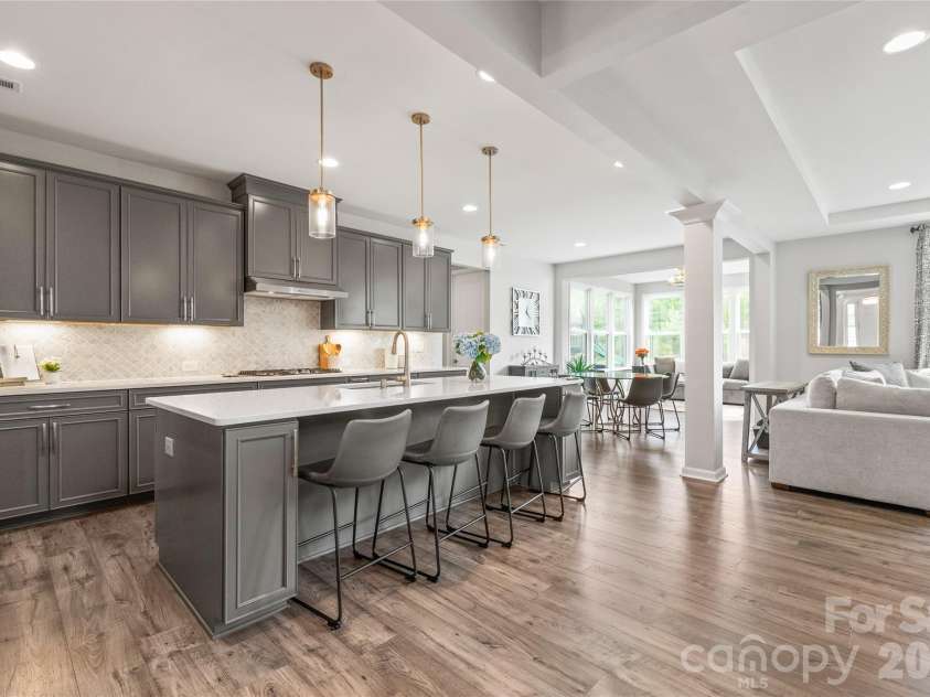 6440 Ancient Way, Fort Mill, SC 29707.  MLS# CAR4413430, YatesRealty ID 45254. Illuminated by ambient under-cabinet lighting, crisp recessed lights, and beautiful statement pendants over the island, this kitchen glows with effortless warmth and style.