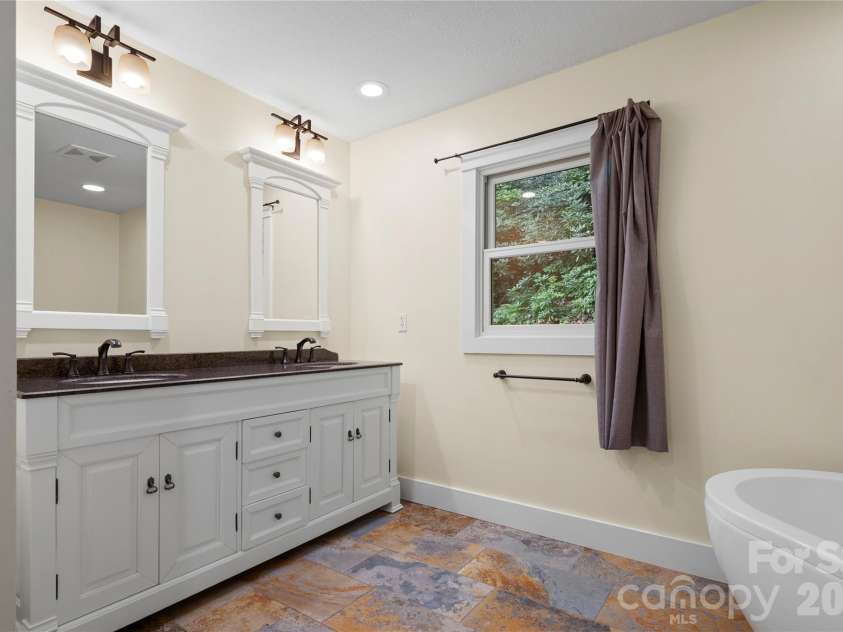 236 Holland Drive, Black Mountain, NC 28711.  MLS# CAR4412802, YatesRealty ID 45307. This spacious primary ensuite bathroom includes a double vanity, a large soaking tub, a separate freestanding shower, and two closets (one generous walk-in closet).