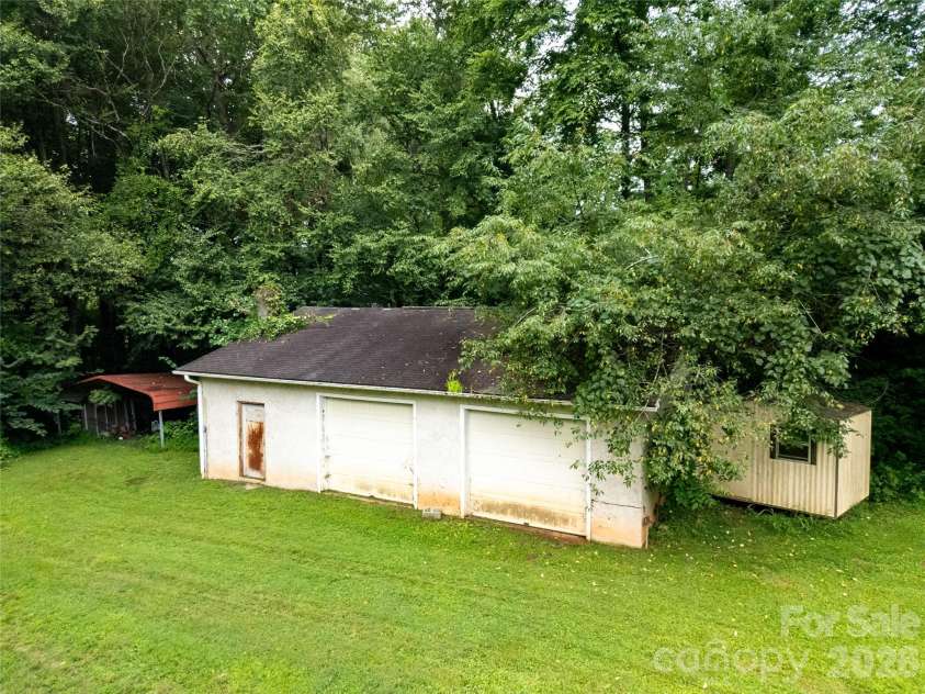 15 Windy Canyon Road, Candler, NC 28715.  MLS# CAR4410438, YatesRealty ID 45308. Two-car garage / workshop, and an old storage shed. It is said there is a spring back in the woods behind these buildings! The old aluminum two-car carport structure will not convey.