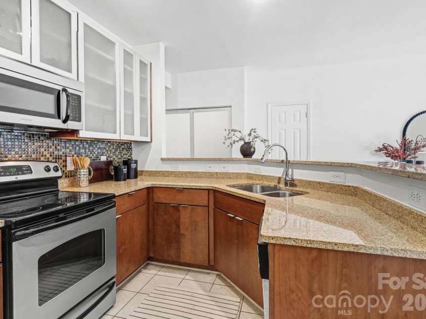 525 Graham Street, Charlotte, NC 28202.  MLS# CAR4341824, YatesRealty ID 4546. Well-appointed kitchen featuring granite countertops, stainless appliances, and glass-front cabinetry.
