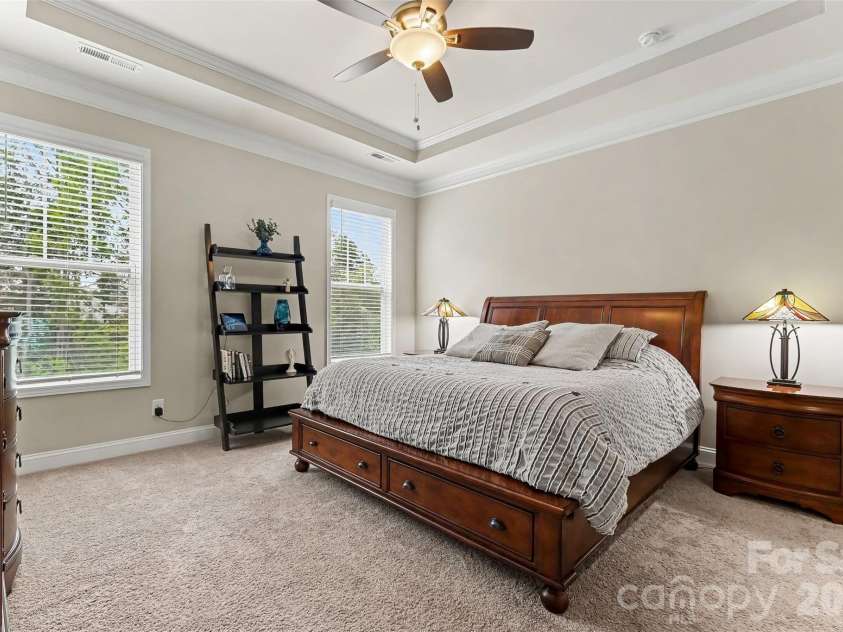 676 Latrobe Drive, Iron Station, NC 28080.  MLS# CAR4401657, YatesRealty ID 45521. Spacious primary bedroom featuring an elegant tray ceiling, creating a bright and inviting retreat