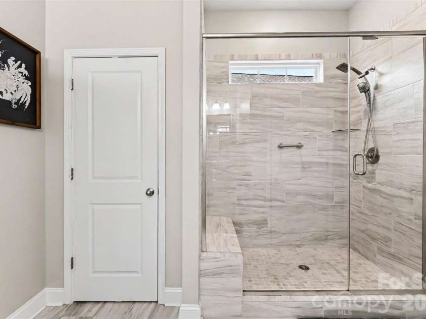 676 Latrobe Drive, Iron Station, NC 28080.  MLS# CAR4401657, YatesRealty ID 45521. Spacious walk-in shower with beautiful tile surround and built in bench