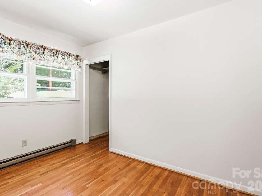 27 McGee Circle, Fairview, NC 28730.  MLS# CAR4415904, YatesRealty ID 45673. Bright bedroom features hardwood floors, multiple windows, closet space, and baseboard heating.