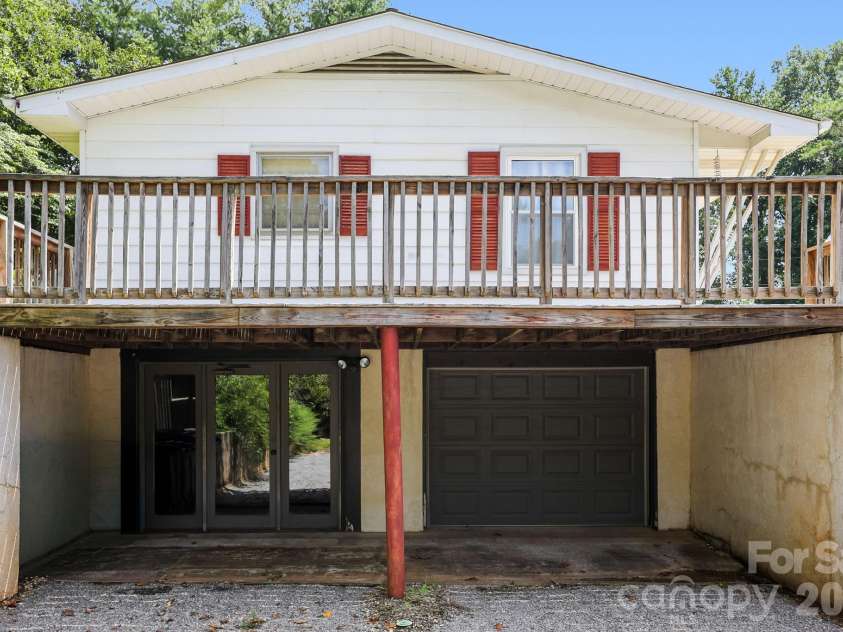 27 McGee Circle, Fairview, NC 28730.  MLS# CAR4415904, YatesRealty ID 45673. Exterior view featuring the expansive elevated deck with access to the lower-level garage and additional entry.