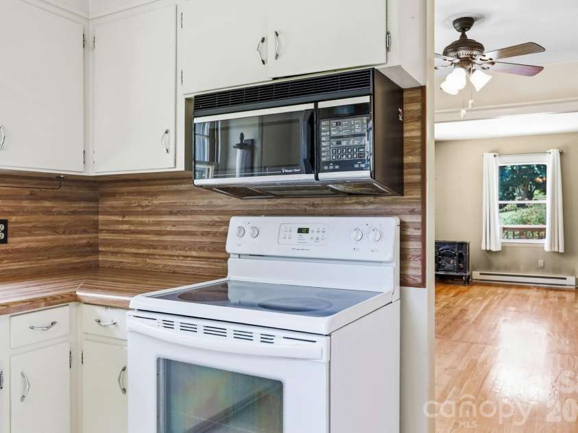 27 McGee Circle, Fairview, NC 28730.  MLS# CAR4415904, YatesRealty ID 45673. Kitchen cooking area with extensive cabinetry, wraparound counters, electric range, and microwave.
