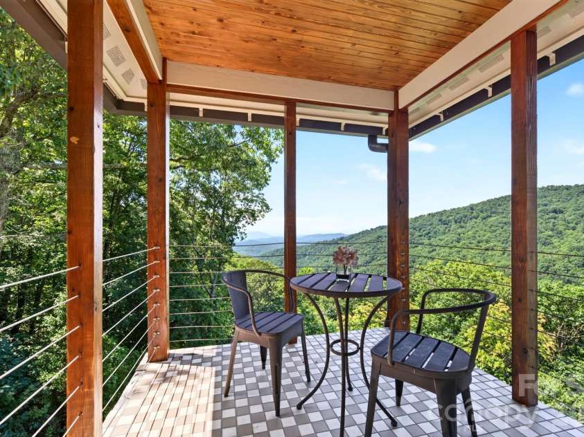 69 Rock Springs Road, Fairview, NC 28730.  MLS# CAR4413478, YatesRealty ID 45887. Premium outdoor living space with timber posts and cable railings captures long-range mountain and water views. Slate flooring and custom finishes create an inviting retreat for entertaining or peaceful contemplation o