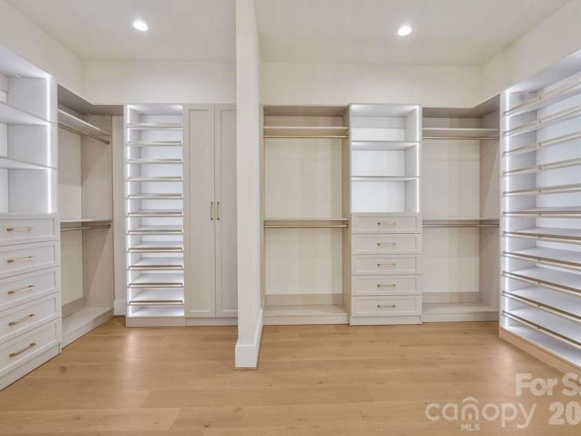 21216 Rio Oro Drive, Cornelius, NC 28031.  MLS# CAR4425303, YatesRealty ID 45943. Custom-designed primary closet featuring integrated LED-lit shelving, extensive built-in storage, and a refined boutique-inspired feel.