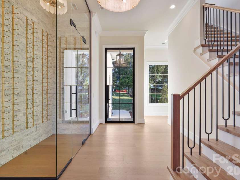 21216 Rio Oro Drive, Cornelius, NC 28031.  MLS# CAR4425303, YatesRealty ID 45943. Grand foyer featuring a dramatic 10' steel front door and custom wine display, creating a striking first impression upon entry.