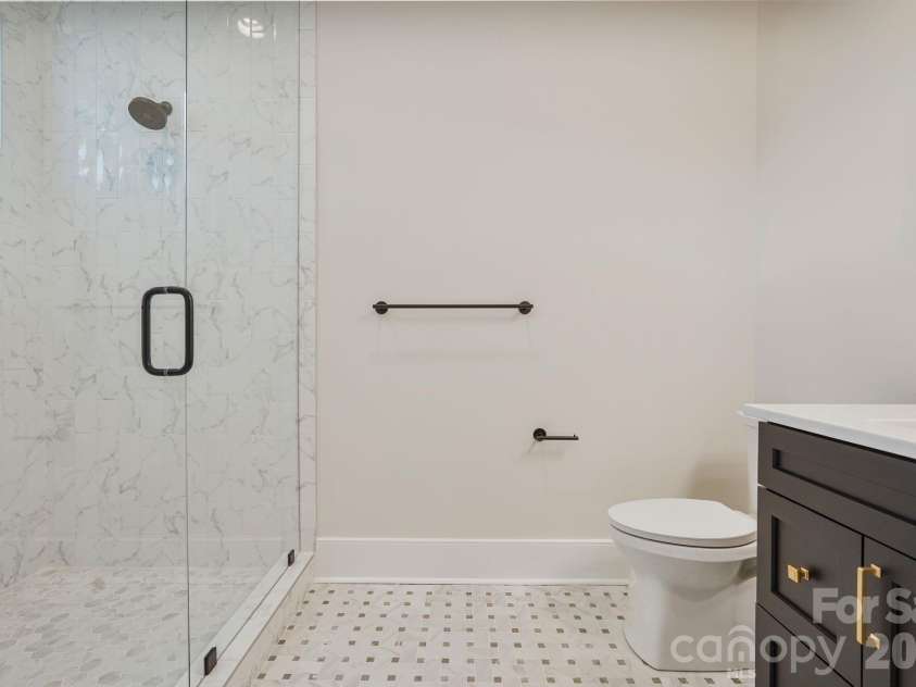 21216 Rio Oro Drive, Cornelius, NC 28031.  MLS# CAR4425303, YatesRealty ID 45943. Main level guest ensuite with shower thoughtfully framed to a 10' ceiling height to help retain warmth and steam, with a transom window bringing in natural light while maintaining privacy.
