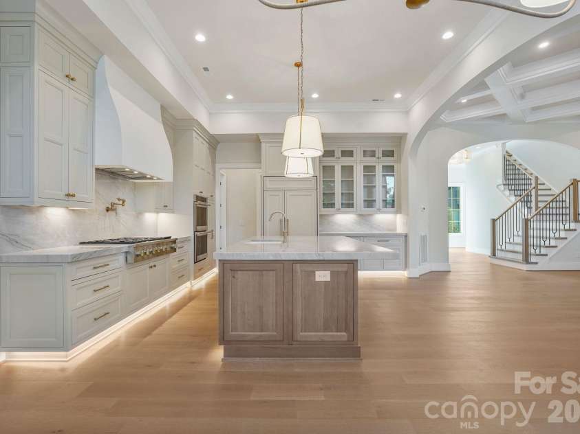 21216 Rio Oro Drive, Cornelius, NC 28031.  MLS# CAR4425303, YatesRealty ID 45943. Side view of the kitchen highlighting seamlessly integrated panel-ready appliances, glass-front upper cabinetry, and refined custom finishes throughout.