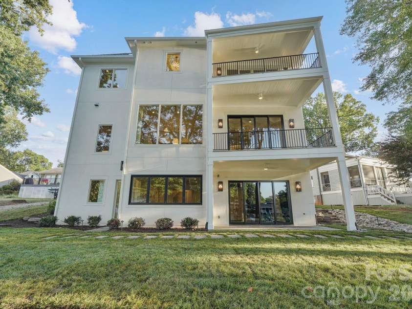21216 Rio Oro Drive, Cornelius, NC 28031.  MLS# CAR4425303, YatesRealty ID 45943. Stunning rear elevation showcasing expansive windows and multiple porches designed to maximize natural light and outdoor living.