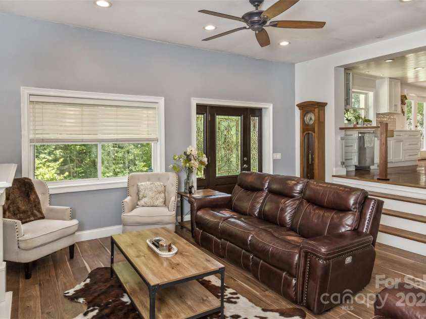 3882 New Leicester Highway, Leicester, NC 28748.  MLS# CAR4168284, YatesRealty ID 4603. View of the living room from the fireplace side, with front door and stairs up to kitchen