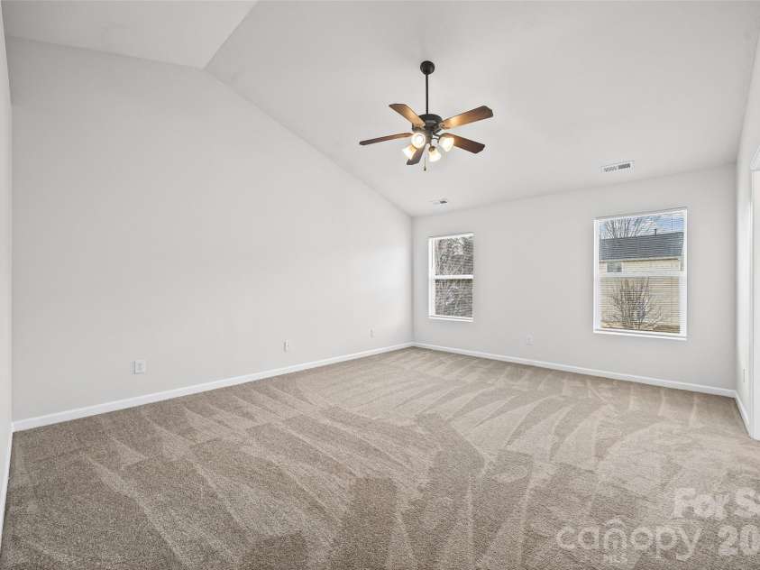 2051 Moss Creek Drive, Harrisburg, NC 28075.  MLS# CAR4344478, YatesRealty ID 4674. Ceiling fan adorns the vaulted primary bedroom ceiling.