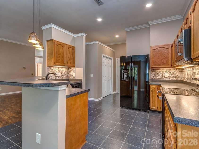 11320 Hunters Landing Drive, Charlotte, NC 28273.  MLS# CAR4426224, YatesRealty ID 46784. Lovely Kitchen with Solid Surface Countertops, Pendant Lighting, Custom Backsplash, Tile Flooring, Crown Molding, Recessed and Under Cabinet Lighting, & Eat At Bar that is perfect for Entertaining!