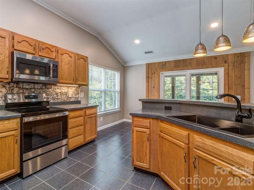 11320 Hunters Landing Drive, Charlotte, NC 28273.  MLS# CAR4426224, YatesRealty ID 46784. Lovely Kitchen with Solid Surface Countertops, Pendant Lighting, Custom Backsplash, Tile Flooring, Crown Molding, Recessed and Under Cabinet Lighting, & Eat At Bar that is perfect for Entertaining!