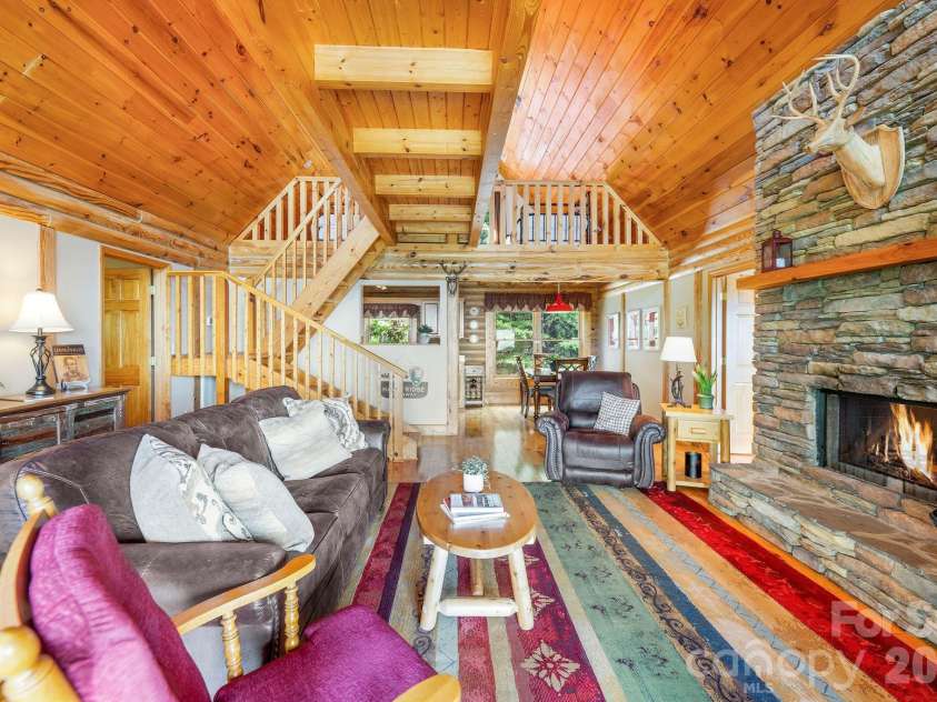 175 Big Rock Road, Bostic, NC 28018.  MLS# CAR4416989, YatesRealty ID 46907. Dramatic stacked-stone fireplace anchors the warm and inviting great room, featuring soaring wood ceilings, exposed beams, an open loft, and high-quality leather furnishings—all included for a truly turnkey mountain cabin r