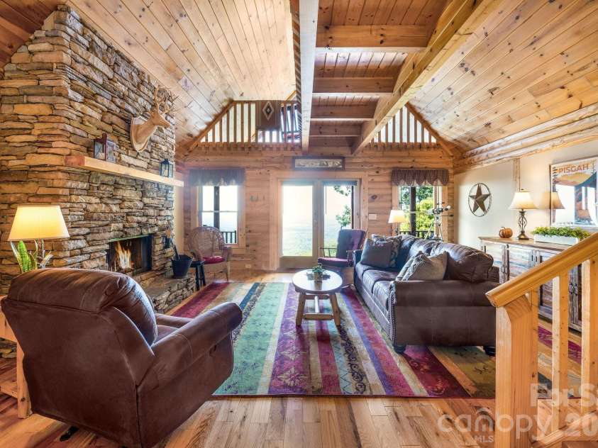 175 Big Rock Road, Bostic, NC 28018.  MLS# CAR4416989, YatesRealty ID 46907. Dramatic stacked-stone fireplace anchors the warm and inviting great room, featuring soaring wood ceilings, exposed beams, an open loft, and high-quality leather furnishings—all included for a truly turnkey mountain cabin r