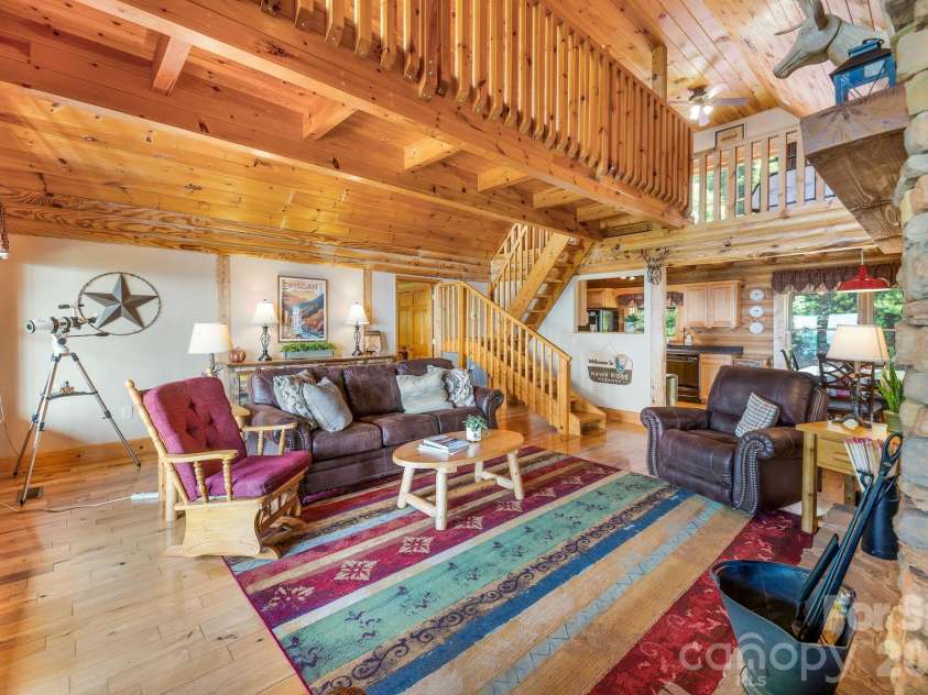 175 Big Rock Road, Bostic, NC 28018.  MLS# CAR4416989, YatesRealty ID 46907. Dramatic stacked-stone fireplace anchors the warm and inviting great room, featuring soaring wood ceilings, exposed beams, an open loft, and high-quality leather furnishings—all included for a truly turnkey mountain cabin r