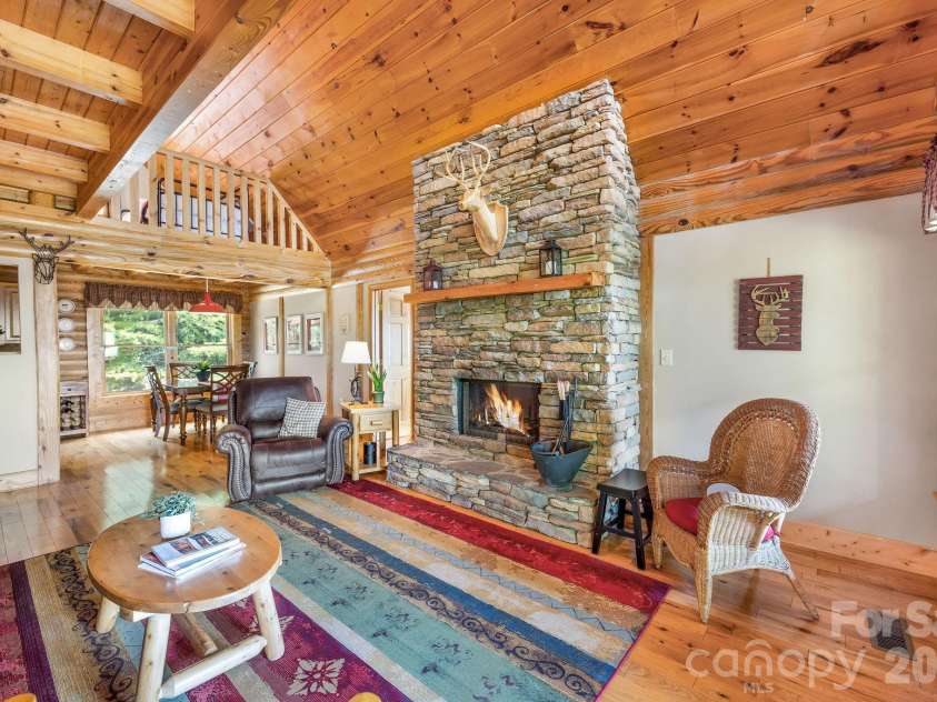 175 Big Rock Road, Bostic, NC 28018.  MLS# CAR4416989, YatesRealty ID 46907. Dramatic stacked-stone fireplace anchors the warm and inviting great room, featuring soaring wood ceilings, exposed beams, an open loft, and high-quality leather furnishings—all included for a truly turnkey mountain cabin r