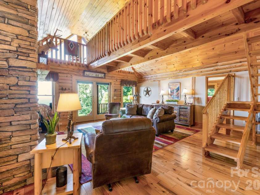 175 Big Rock Road, Bostic, NC 28018.  MLS# CAR4416989, YatesRealty ID 46907. Dramatic stacked-stone fireplace anchors the warm and inviting great room, featuring soaring wood ceilings, exposed beams, an open loft, and high-quality leather furnishings—all included for a truly turnkey mountain cabin r