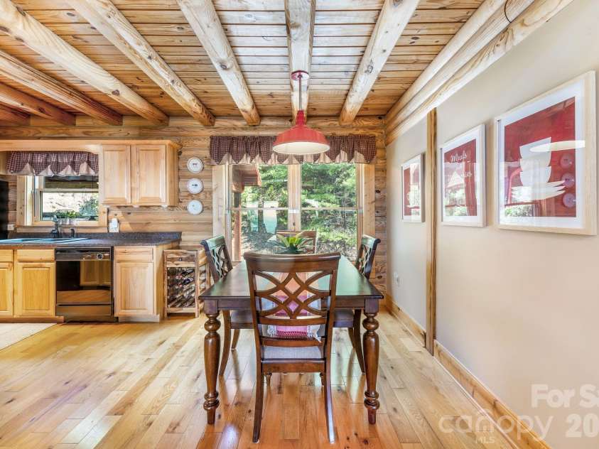 175 Big Rock Road, Bostic, NC 28018.  MLS# CAR4416989, YatesRealty ID 46907. Inviting dining area open to the kitchen, featuring beautiful hardwood floors, exposed log beams, abundant natural light, and the warm rustic character of the cabin throughout.