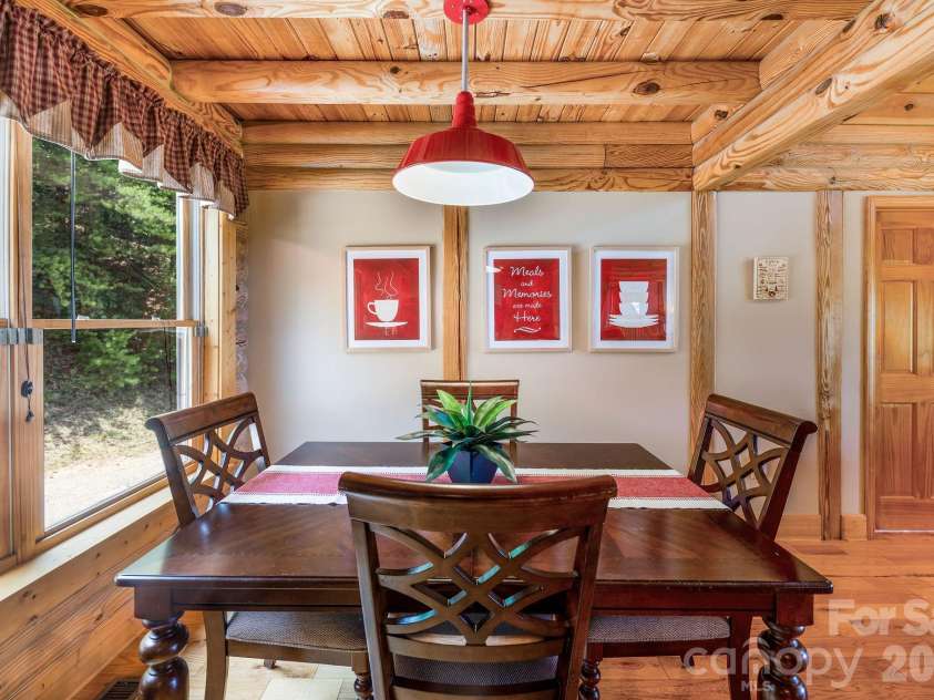 175 Big Rock Road, Bostic, NC 28018.  MLS# CAR4416989, YatesRealty ID 46907. Inviting dining area open to the kitchen, featuring beautiful hardwood floors, exposed log beams, abundant natural light, and the warm rustic character of the cabin throughout.