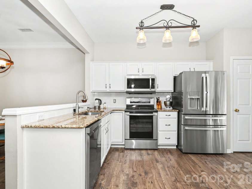 6614 Beverly Springs Drive, Charlotte, NC 28270.  MLS# CAR4418145, YatesRealty ID 47033. Kitchen with white cabinetry, granite counters and updated SS appliances.