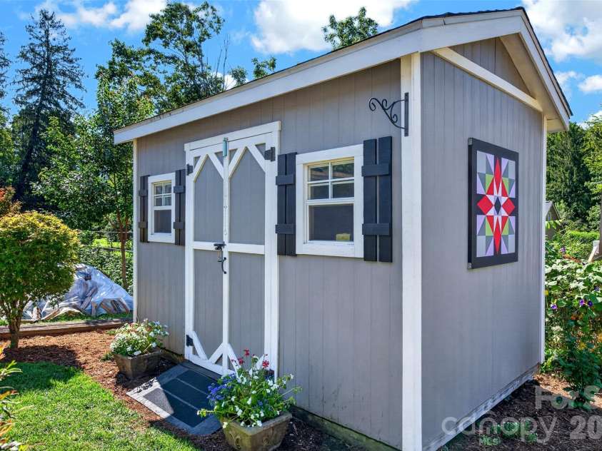 206 Kerlee Heights Road, Black Mountain, NC 28711.  MLS# CAR4414870, YatesRealty ID 47078. Coordinating board-and-batten siding, decorative doors and classic shutters make the storage building feel like a charming extension of the cottage.